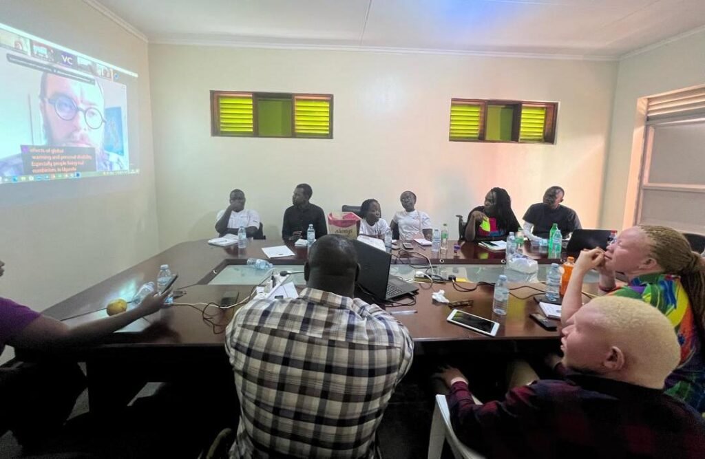 Photo of a group of 10 people sitting around a table in a conference room, watching a projector, participating in the Venture training programme.